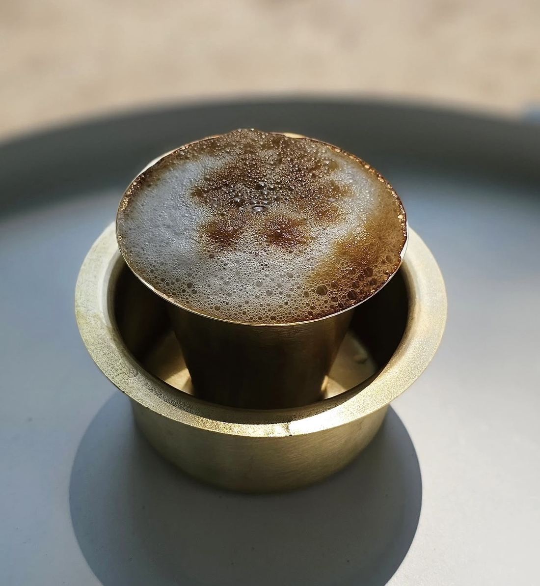 Filter coffee served in a traditional brass davara and tumbler